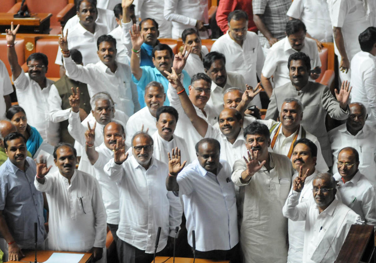 Members of the ruling party in the Karnataka Legislative Assembly show the victory sign after successfully winning the trust vote session for the newly sworn in Chief Minister of the JD(S)-Congress coalition government in the Karnataka Assembly at the Vid