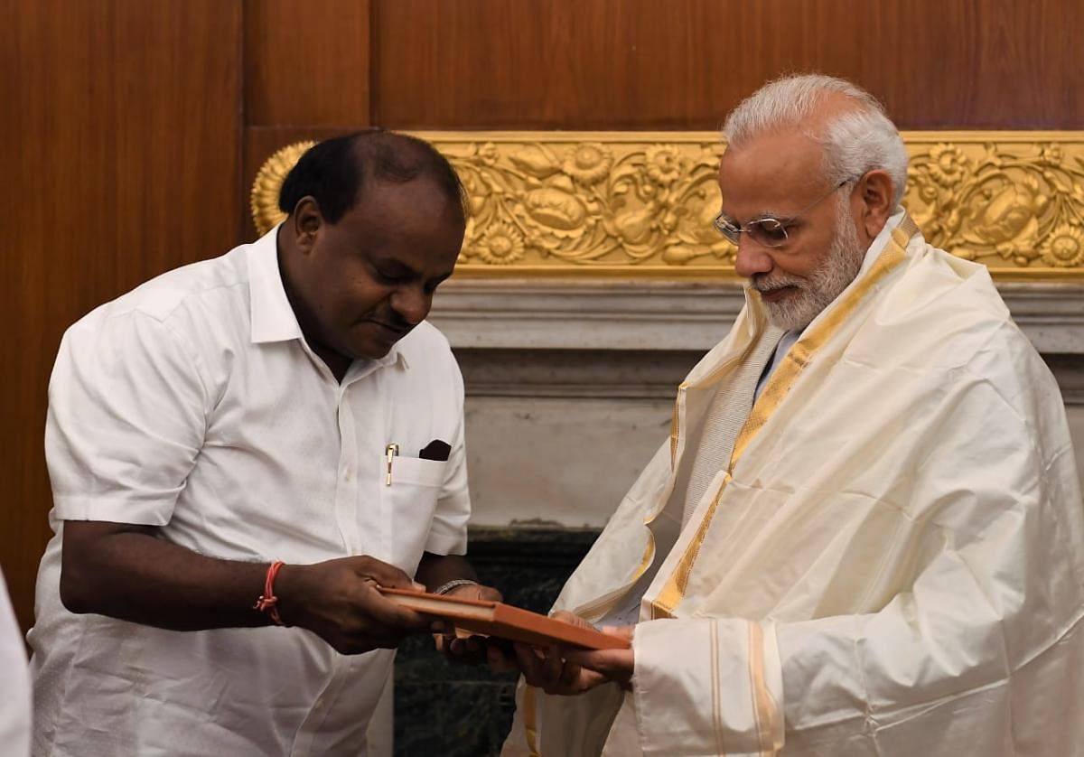 Karnataka Chief Minister H D Kumaraswamy presents a book, "The Open Eyes: A journey through Karnataka", written by renowned poet Dom Moraes, to Prime Minister Narendra Modi, in New Delhi on Monday. (Pic released by Press Information Bureau)