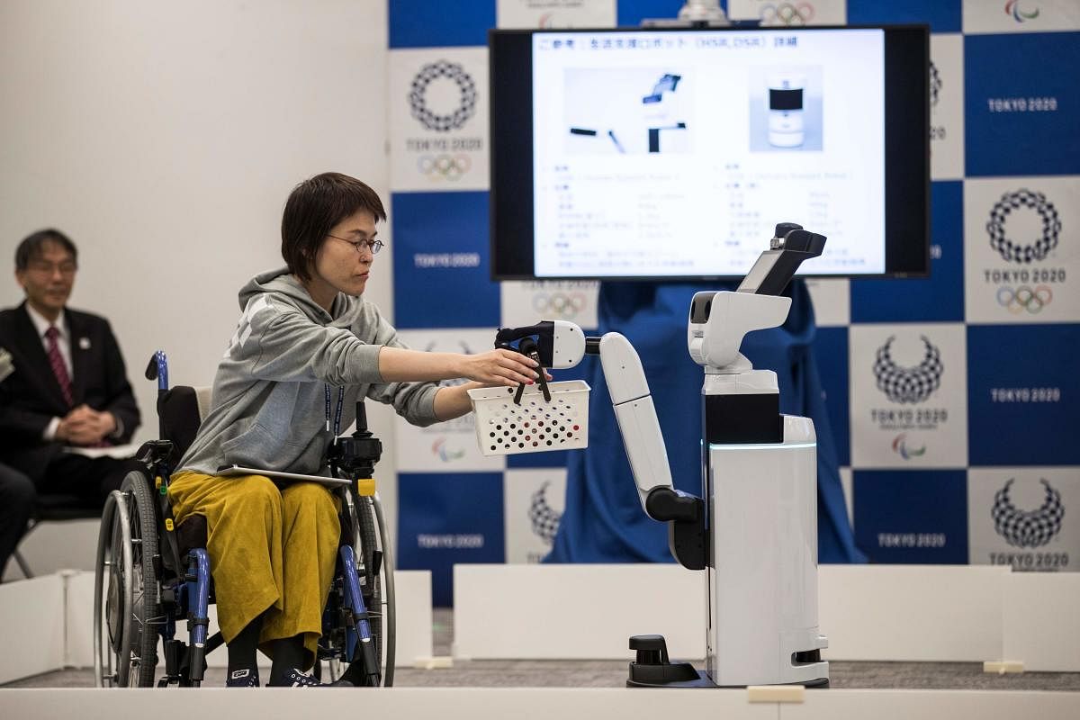 INNOVATIVE: Toyota's Human Support Robot (right) delivers a basket to a woman in a wheelchair during a demonstration of the Tokyo 2020 Robot Project. AFP 