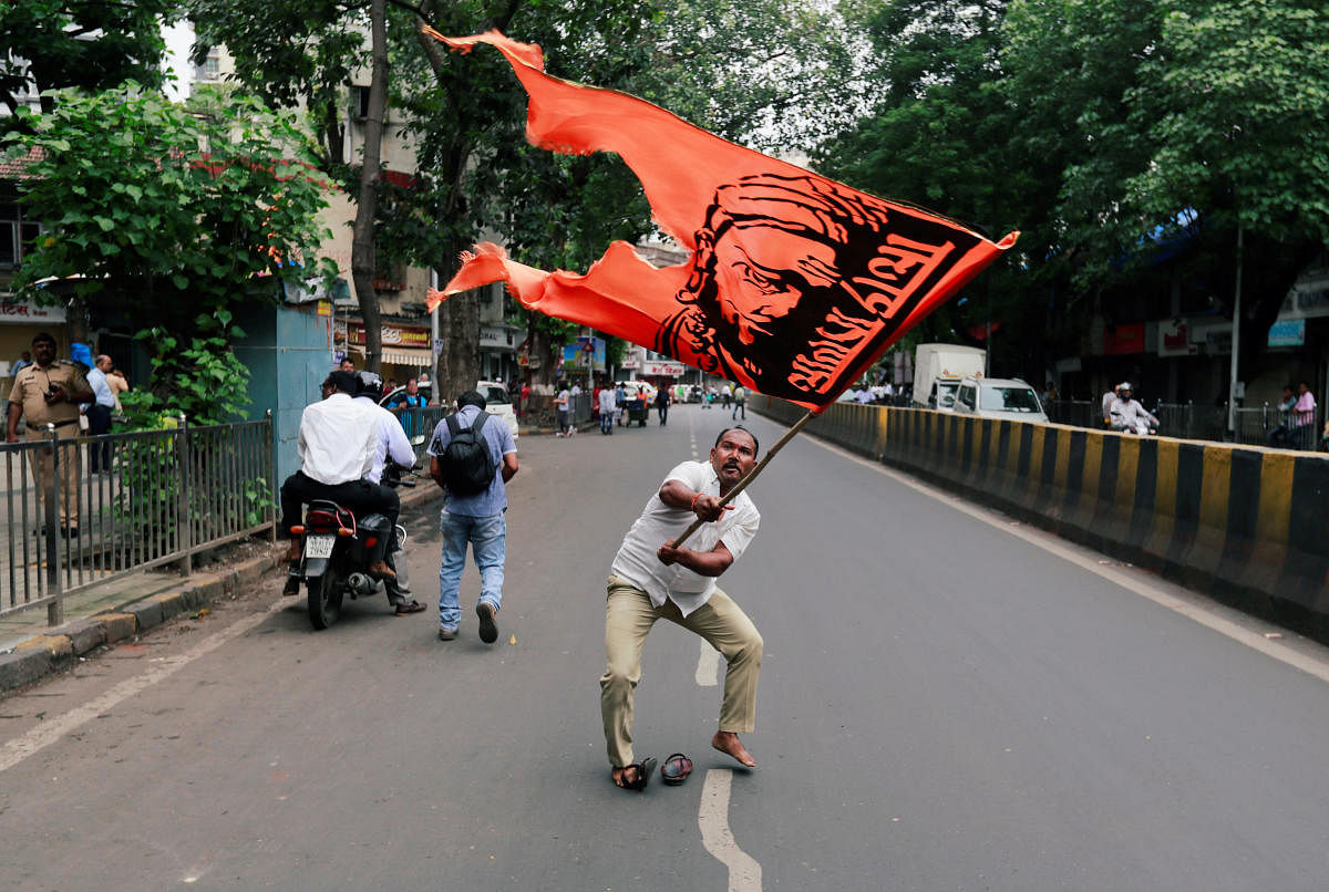 A man waves a flag as he blocks a road during a protest, organised by Maharashtra state's Maratha community, to press their demands for reserved quotas in government jobs and college places for students in Mumbai, July 25, 2018. REUTERS photo.