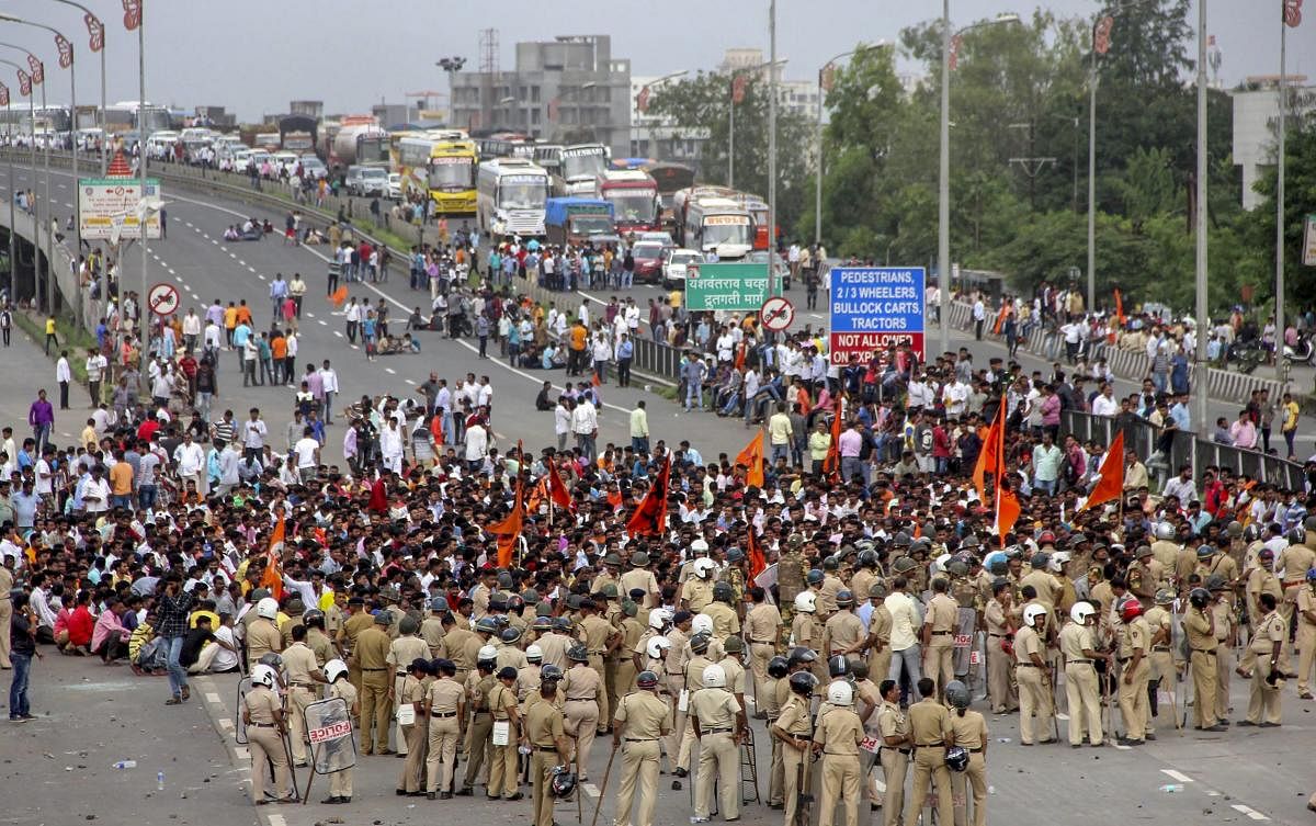 Maratha Kranti Morcha protesters block a road, as police personnel stand by during their statewide bandh called for reservations in jobs and education, in Navi Mumbai. PTI photo.