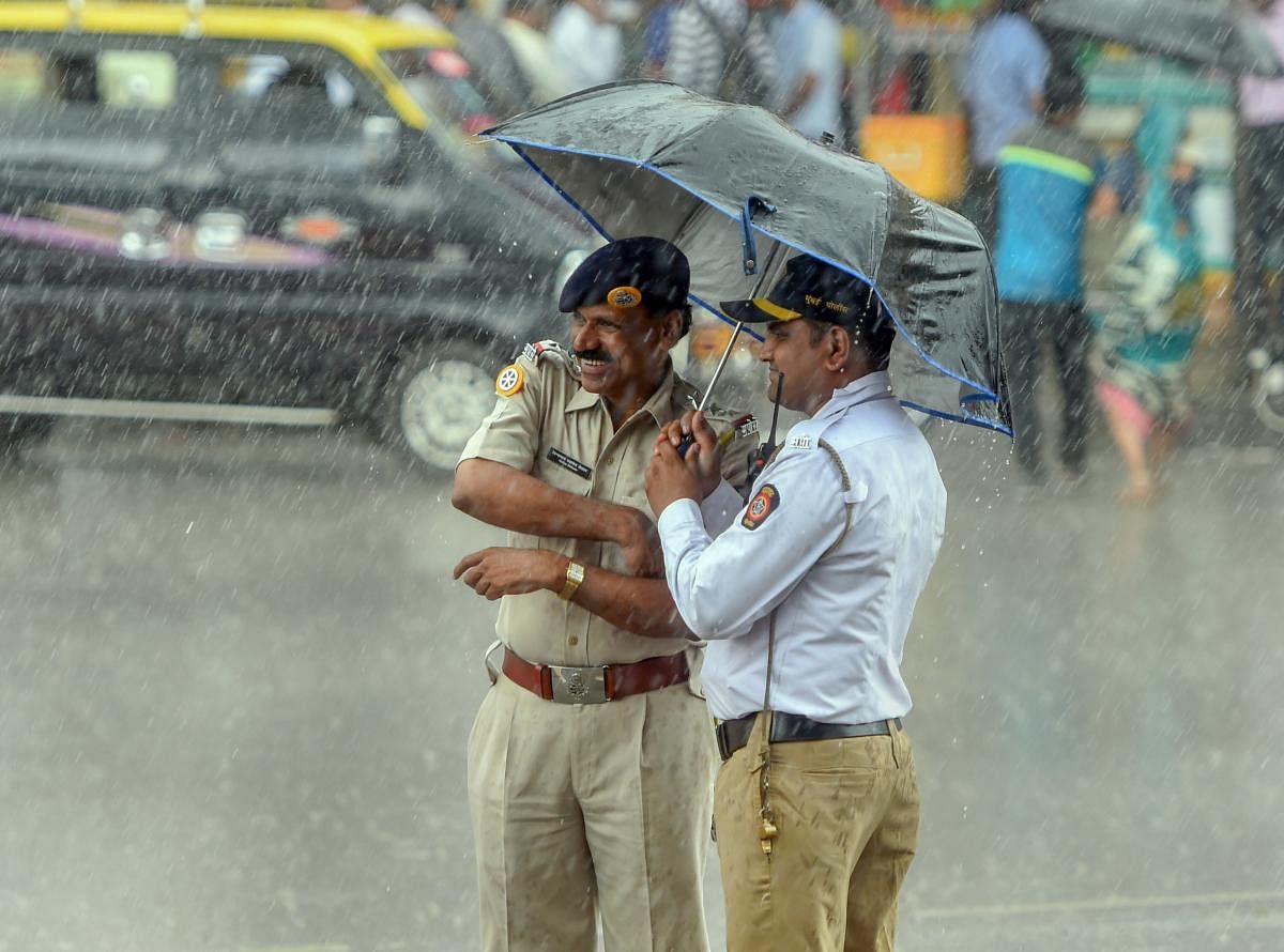 Police personnel take cover under an umbrella during Monsoon rains, in Mumbai. Reuters file photo for representation. 