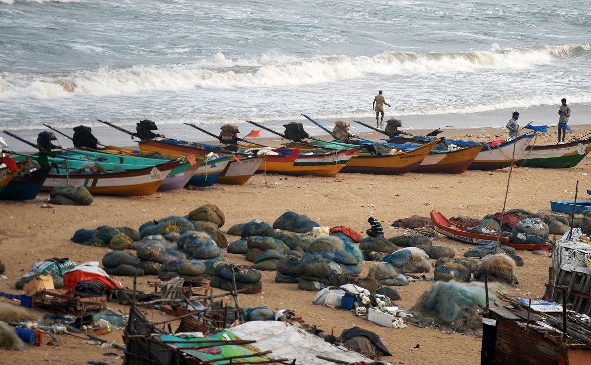 Fishermen stand along a beach beside fishing boats on the coast of the Bay of Bengal, in Chennai on Monday. Tropical Cyclone Gaja is forecasted to make a landfall on the southern coast of India, between Chennai and Nagapattinam on November 15. AFP