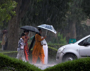 People walk with their umbrellas during rain at Rajpath in New Delhi on Saturday. PTI Photo
