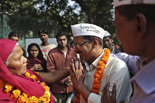 'Aam Aadmi' party candidate Arvind Kejriwal, center, seeks the blessings of a voter, left, ahead of the Delhi state assembly elections in New Delhi, India, Monday, Dec. 2, 2013.  AP