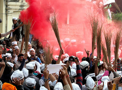 Aam Aadmi Party workers wave brooms (party symbol) as they celebrate the party's excellent show in Delhi Assembly elections, in New Delhi on Sunday. PTI Photo