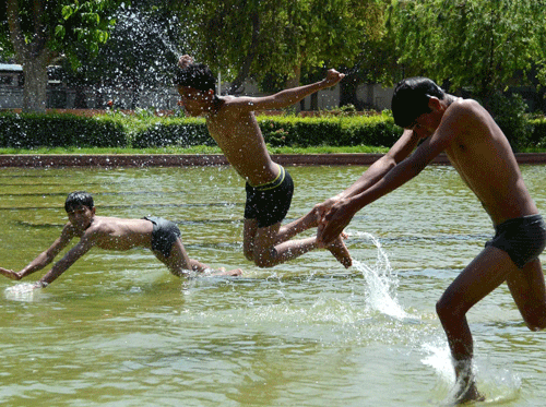 Boys diving in a water channel to beat the scorching heat at India Gate lawn in New Delhi on Monday. PTI Photo