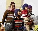 A family shields itself against the cold as they walk at India Gate in New Delhi. PTI
