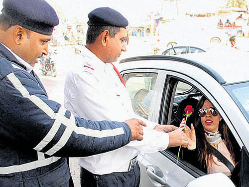 A traffic policeman presents a rose to a commuter for  following traffic rules in Gurgaon on Saturday. PTI