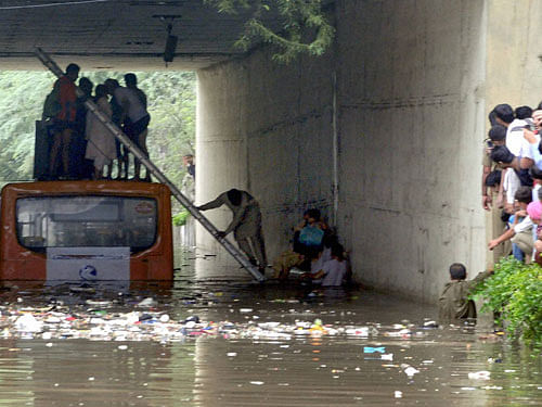 Passengers being rescued after a bus got stuck at the flooded Jakhira underpass following heavy rain in  New Delhi on Wednesday. PTI