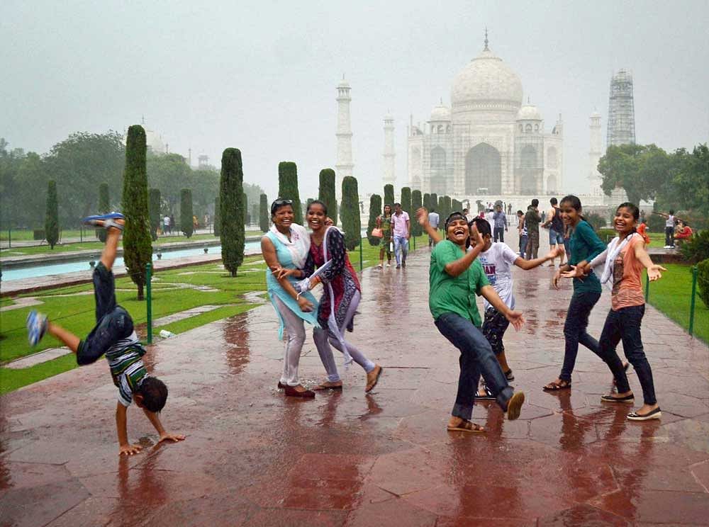 Tourists enjoy the rainy weather at the Taj Mahal in Agra on Sunday. PTI Photo