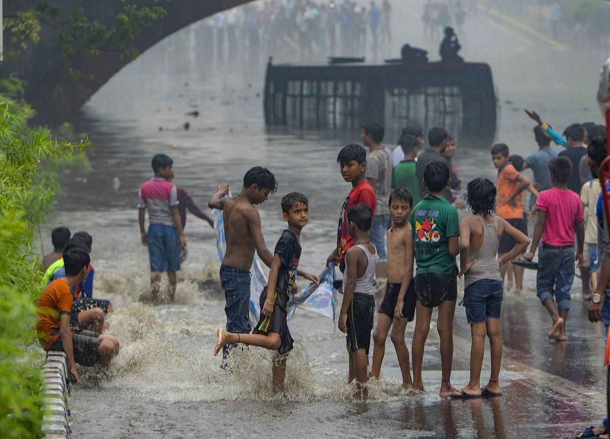 Children play near a waterlogged street under Minto Bridge during a monsoon rain in New Delhi on Monday. PTI