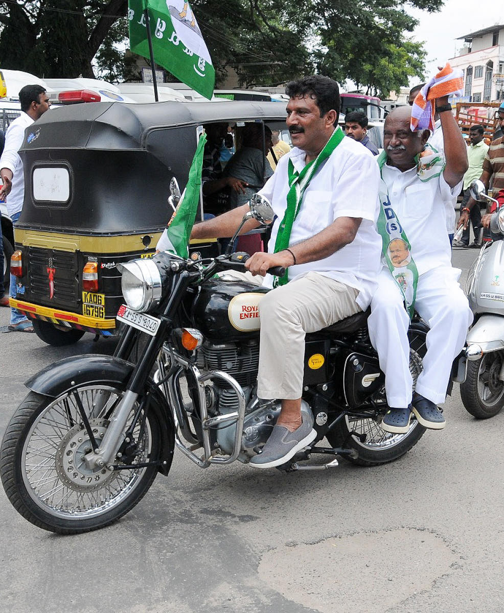 time to violate rules: JD(S) leader Azeez Abdullah takes party state president A H Vishwanath for a ride, on a mobike without helmets, in Mysuru, on Monday.