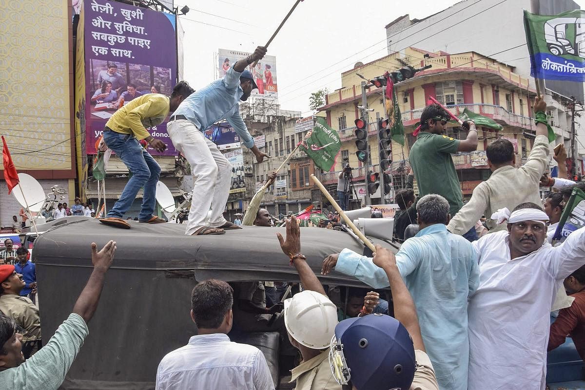 Jan Adhikar Party activists climb on a police vehicle during the Bharat Bandh called over fuel price hike in Patna on Monday. PTI