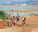 Youths engaged in washing tank silt to get filtered sand in Narasapura tank. DH Photo
