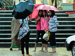in rain: (Clockwise) A bunch of girls busy posing for a group photo, under the cover of umbrellas during rain in Mysore on Thursday. People wade through puddle of water near K&#8200;R&#8200;Circle. The waterlogged MCC&#8200;compound. A boy clears water that had gushed into his house in a low-lying area in Udaygiri.  dh photos