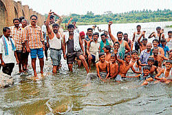 Residents of Rampura stage a protest by getting into the river near the western bridge in Srirangapatna on Sunday. dh photo