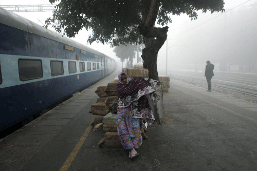A passenger waits for her train on a foggy morning at a railway station in New Delhi, India, Tuesday, Dec. 17, 2013. Delhi and other parts of northwest India witnessed the first dense fog of the season that threw air and rail traffic out of gear, more than a week before it was expected, according to local news reports. AP photo