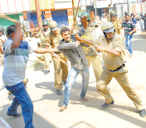 Police cane a protester in Chikmagalur on Saturday. DH photo