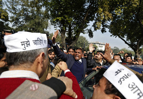 A security personnel (C) tries to maintain order during a protest by Aam Aadmi (Common Man) Party (AAP) supporters next to a car carrying Delhi's Chief Minister Arvind Kejriwal (not pictured) in New Delhi January 20, 2014. Kejriwal and his supporters launched a sit-in against the city police on Monday, creating traffic chaos and a standoff with hundreds of officers in the latest radical step by the anti-graft crusader who has shaken up a national election. REUTERS
