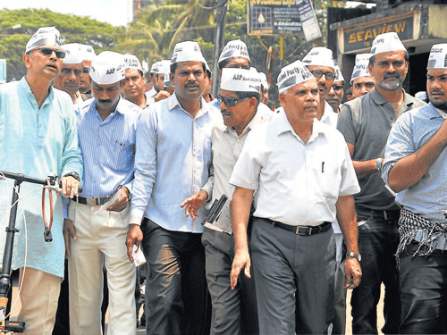AAP candidate M R Vasudeva along with supporters walk towards DC's office to file his nomination papers on Saturday. DH photo