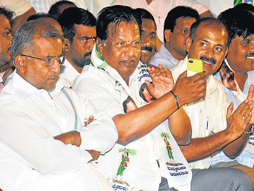 Chamundeshwari MLA G T Devegowda looks pensive, even as legislators Sandesh Nagaraj and Sa Ra Mahesh applaud, following the party workers demand to field Devegowda for Lok Sabha polls from Mysore-Kodagu constituency, in Mysore, on Monday. DH Photo
