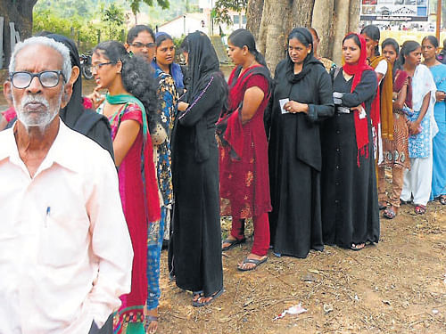 Voters line up to exercise their franchise at Mudigere in Chikmagalur district on Thursday. DH Photo