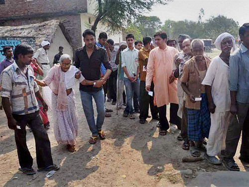 Voters stand in a queue to cast their votes at a polling station in Amethi on Wednesday. PTI Photo