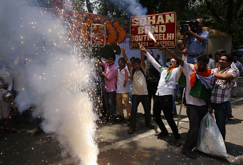 Bharatiya Janata Party (BJP) supporters set off firecrackers and dance to celebrate preliminary results that showed the BJP winning by a landslide, outside the party headquarters in New Delhi, India, Friday, May 16, 2014. AP