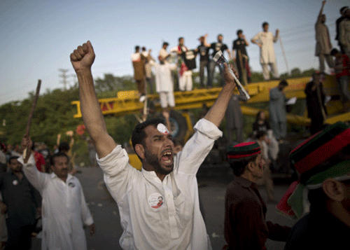 Tens of thousands of protesters used a crane and bolt cutters to force their way past a barricade of shipping containers in the Pakistani capital Tuesday as they marched on parliament to try press the prime minister to resign. AP photo