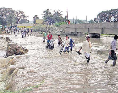 splosh, splosh: The bridge between Hampi and Hospet in Chinnapura village of Kampli taluk, Bellary district,  was submerged following heavy rains on Sunday. dh Photo