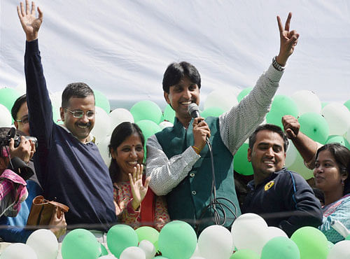 AAP convener Arvind Kejriwal with his wife and Kumar Vishwas waves at party volunteers as they celebrate the party's victory. PTI photo
