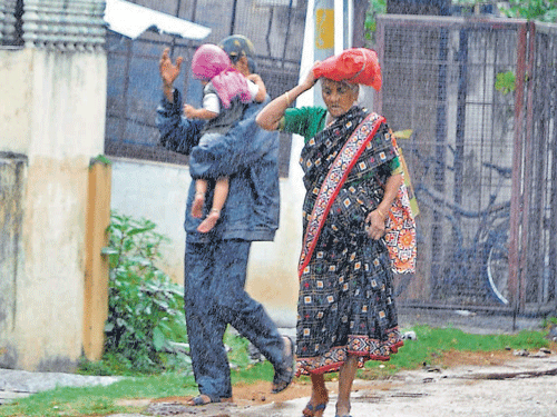 A woman covers her head with a plastic bag to protect herself from rain in Shivamogga on Friday. dh photo