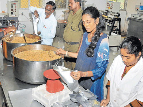 Staffers of the Defence Food Research Food Laboratory pack tomato rice for Chennai's flood victims in Mysuru on Thursday. DH PHOTO