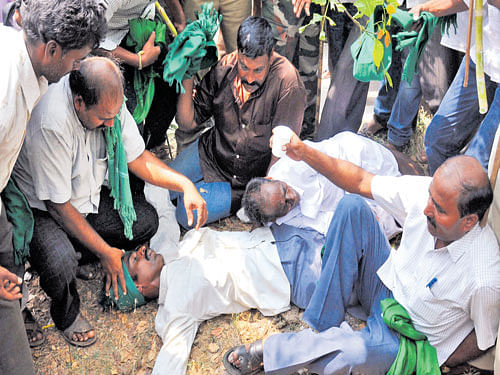 Sugar cane farmers help two protestors who took ill near Chief Minister&#8200;Siddaramaiah's  residence in Mysuru on Thursday. DH photo