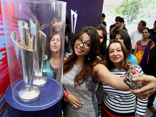 Girls take selfie with ICC T20 World Cup Trophy at event. PTI Photo
