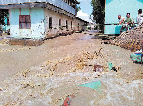 GIGANTIC EFFORT: Residents attempt to prevent a house from being washed away due to flash floods at Kiyamgei in Manipur on Monday.
