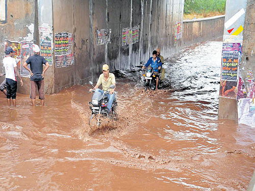 Motorcyclists struggle through a waterlogged underpass in Ballari on Sunday. DH&#8200;Photo