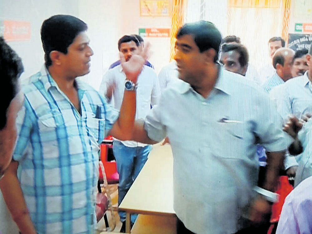 A TV grab shows Hrishikesh Pai (left), a supporter of  Eshwarappa, and Santosh Ballekere, a follower of  Yeddyurappa, having an argument at the BJP office  in Shivamogga on Tuesday.