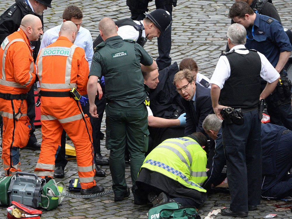 Conservative Member of Parliament Tobias Ellwood, centre, helps emergency services attend to an injured person outside the Houses of Parliament. AP/PTI Photo