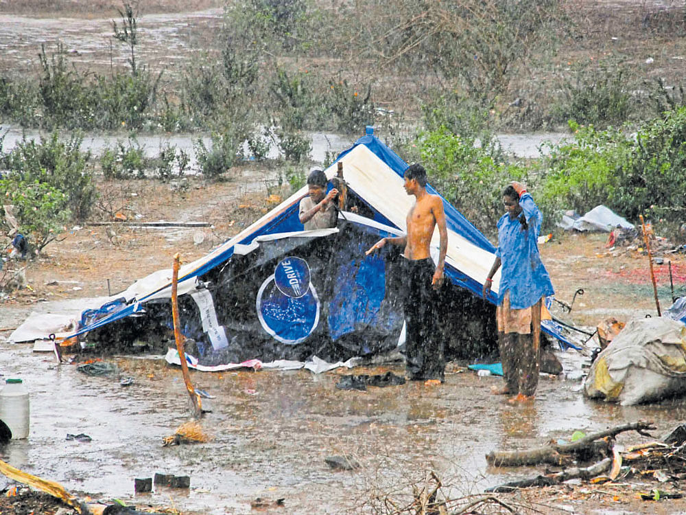 People take shelter in a makeshift house following heavy rain in Hassan on Tuesday.
