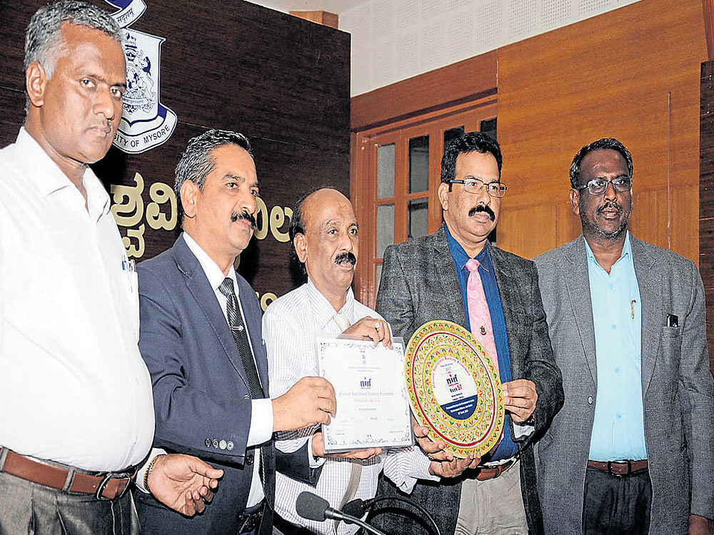 In-charge Vice-Chancellor of University of Mysore (UoM) Dayananda Mane shows the award conferred upon UoM&#8200;by the Union HRD&#8200;ministry at Crawford Hall in Mysuru on Thursday. Director for Planning, Monitoring and Evaluation Board and Nodal Officer for Ranking Lingaraj Gandhi, UoM Registrar R&#8200;Rajanna, Registrar (Evaluation) J&#8200;Somashekar and Finance  Officer Mahadevappa are also seen. DH photo