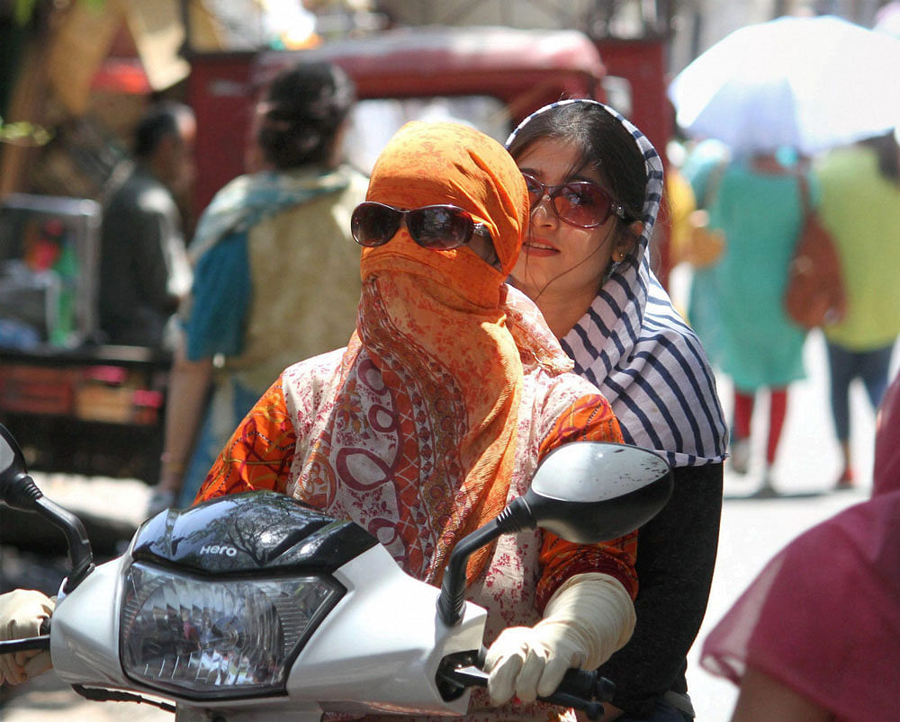 Girls cover their faces with scarves to protect themselves from scorching heat in Jammu on Thursday. PTI Photo