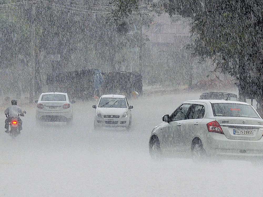respite from heat: Motorists struggle to navigate a road as it rains heavily in Dharwad on Friday. DH Photo