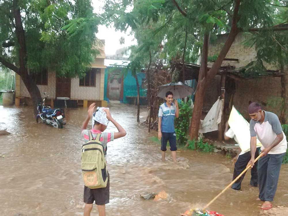 Residents try to prevent rainwater from gushing into houses at Tambralli village in Hagaribommanahalli, Ballari district, on Wednesday. Tambralli received heavy showers for over one-and-a-half hours on Wednesday evening. DH PHOTO