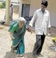 Undeterred: An octogenarian being led by her son to the polling booth at Vemagal on Saturday. DH Photo