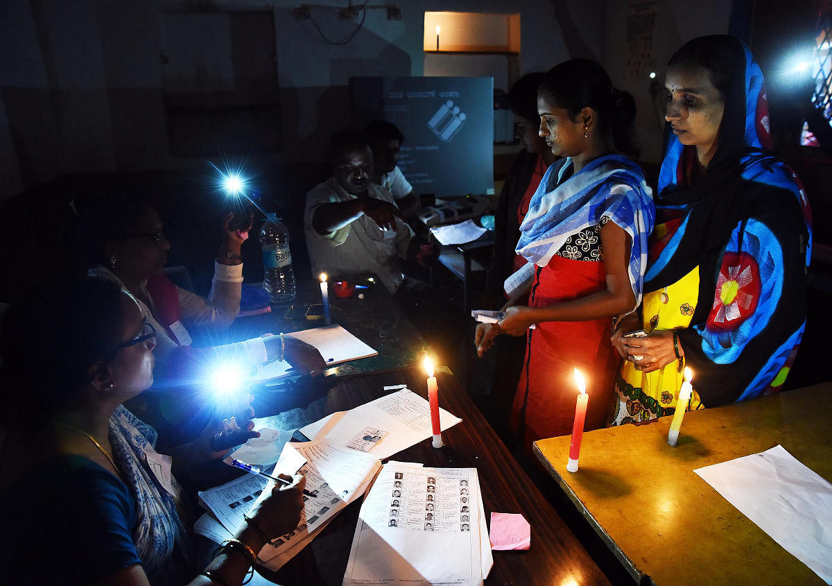 Election officials had to use candles to help voters as there was a power shutdown due to rain at a booth at Hubballi on Saturday. dh photo/Tajuddin Azad