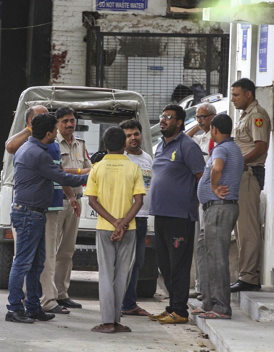 A family member of the 75-year old woman who was among the 11 members of a family found dead at a house in Burari, speaks with police personnel outside Maulana Azad Hospital Mortuary, in New Delhi on Monday. PTI
