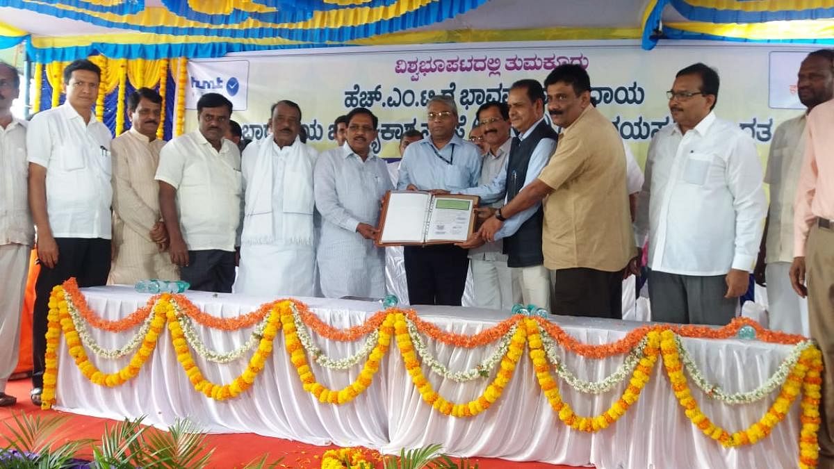 Deputy Chief Minister G Parameshwara and HMT General Manager Patnaik hand over the documents of 109 acres of HMT watch-making unit to Isro representative S Kumaraswamy at a ceremony in Tumakuru on Saturday. MPs S P Muddahanumegowda and B N Chandrappa, min
