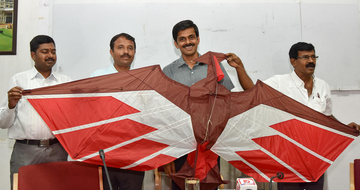 Deputy Commissioner Abhiram G Sanakar displays a kite at the DC's office, in Mysuru, on Friday. Assistant Director for Information and Public Relations R Raju is seen.